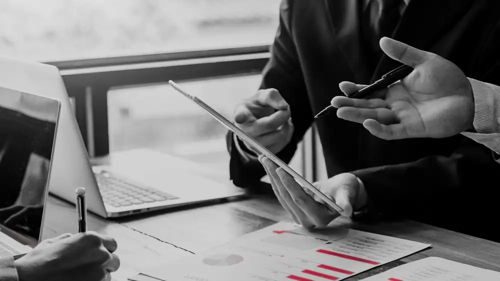 Two advisers reviewing a financial report on a tablet, the kind of data financial institutions must protect