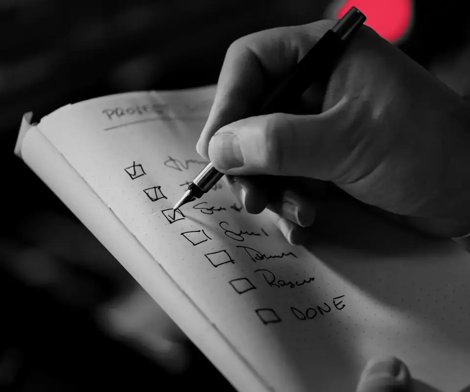 A hand ticking items off a written checklist, the way a compliance audit works through each requirement