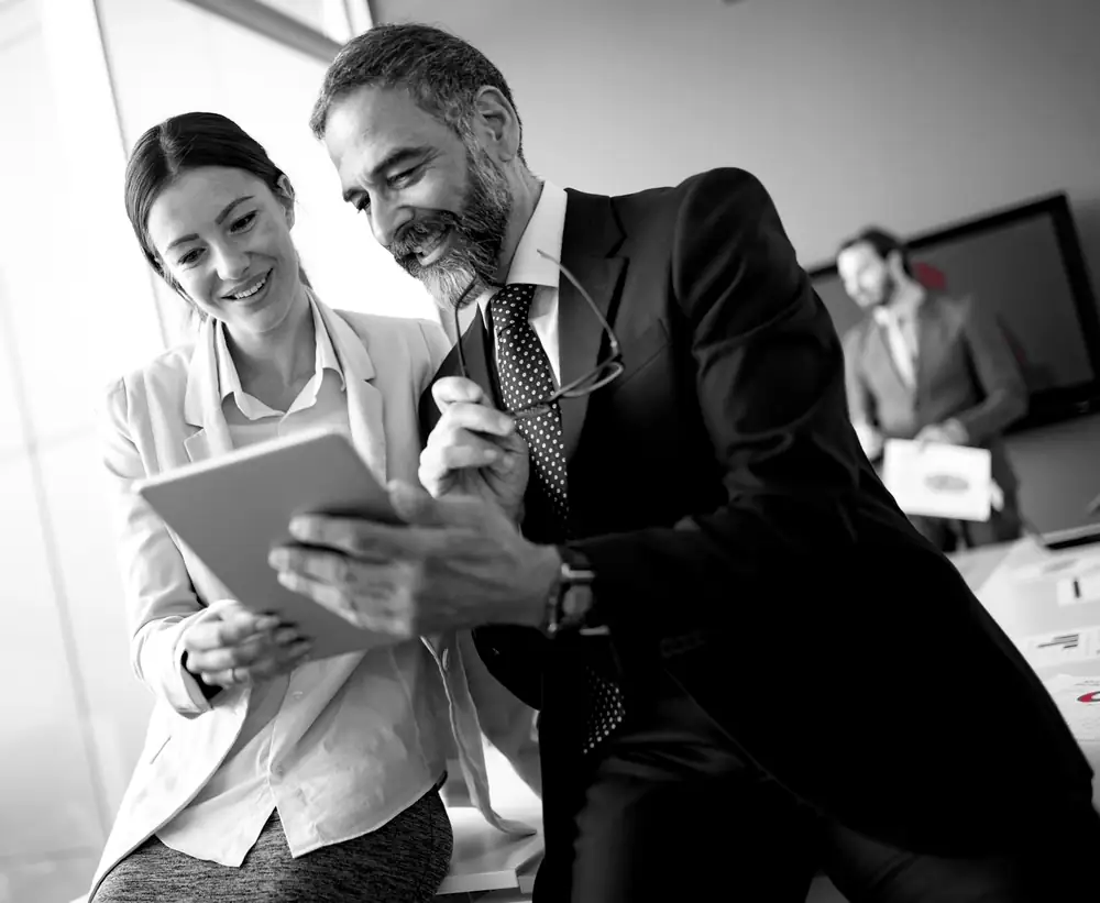 Two executives reviewing results on a tablet, the leadership a risk assessment helps decide where to invest