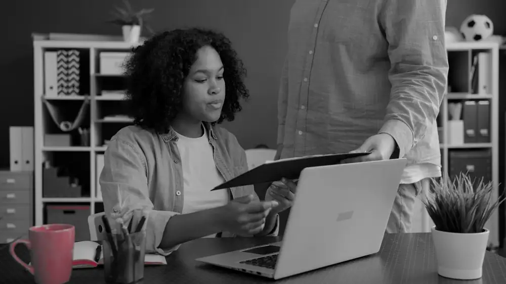 Two colleagues reviewing a document at an office desk while preparing evidence for an audit
