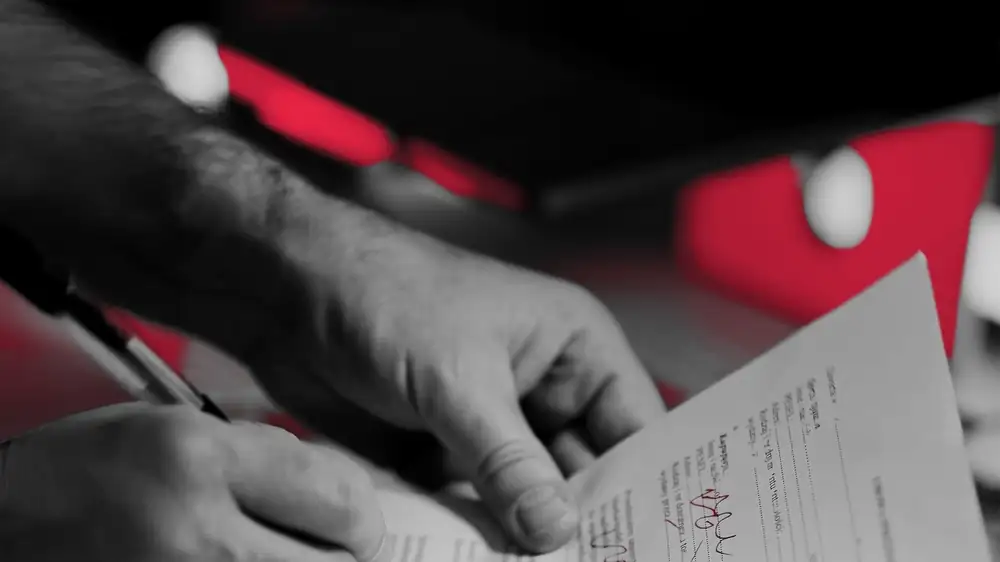 Hands signing a printed policy document, the moment an insurance application becomes binding